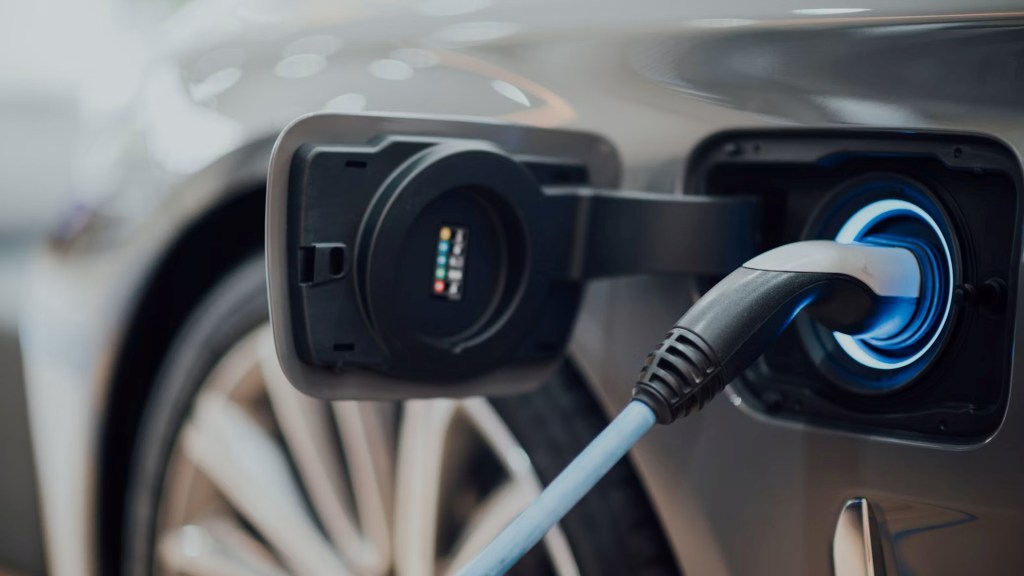 Voiture électrique en charge avec symboles de sources d'énergie fossiles et renouvelables en arrière-plan