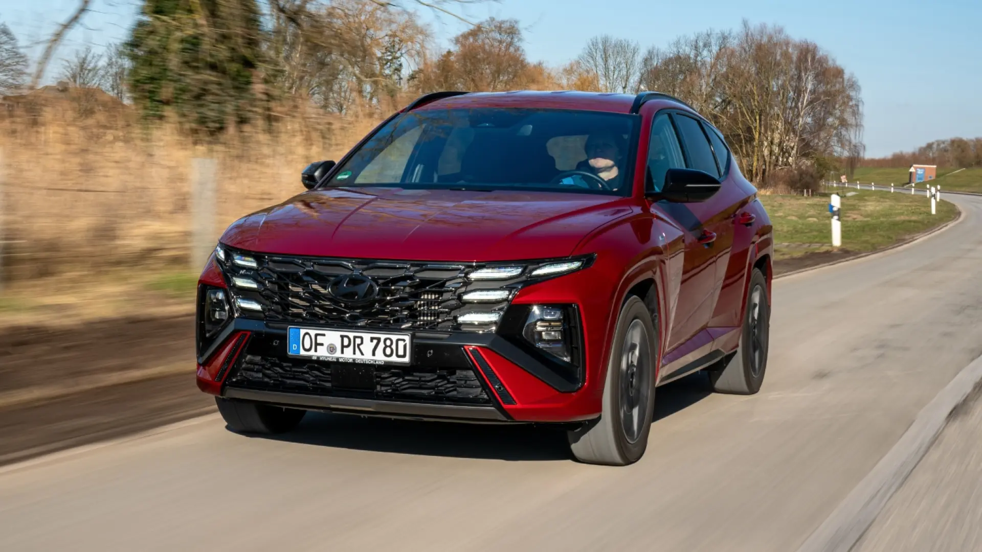 Hyundai Tucson hybride rouge garé, vue de trois quarts avant montrant la calandre et le design extérieur
